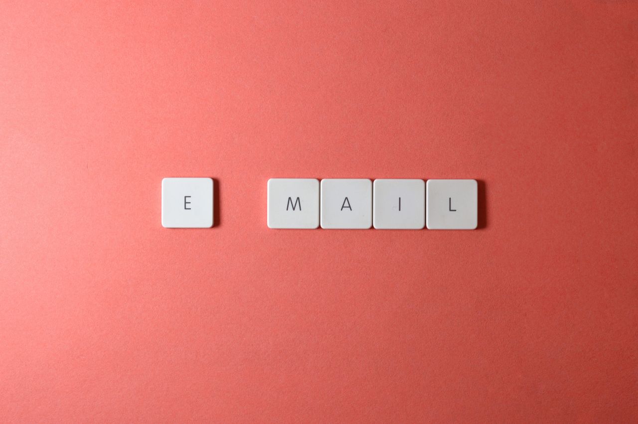 services-02 Vue en flat lay de touches de clavier formant le mot email sur un fond corail.